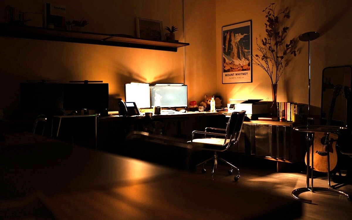 An editing timeline open across a monitor in a dark room, a lit keyboard under it