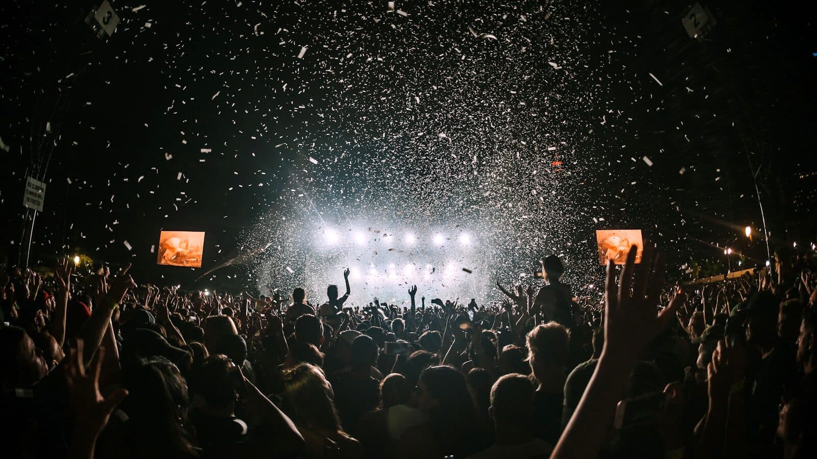 A packed room at a live show, hands in the air in front of a lit stage.